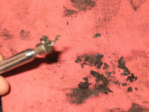 1998 Ford Crown Victoria - metal pick tipped with debris hovers over a red shop towel covered in scraped black sludge.