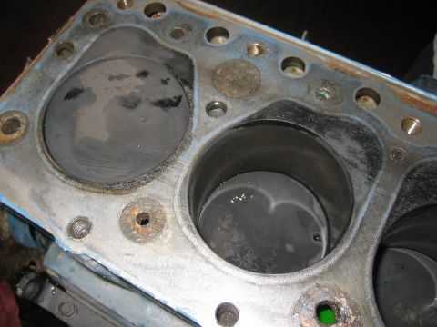 1998 Ford Crown Victoria - View into an engine block showing multiple cylinder bores, a worn deck surface and surrounding head bolt holes.