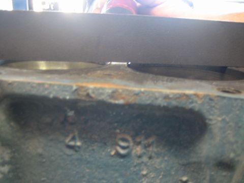 1998 Ford Crown Victoria - Worn side of an engine block with faded cast numbers and a straightedge resting across the cylinder deck.