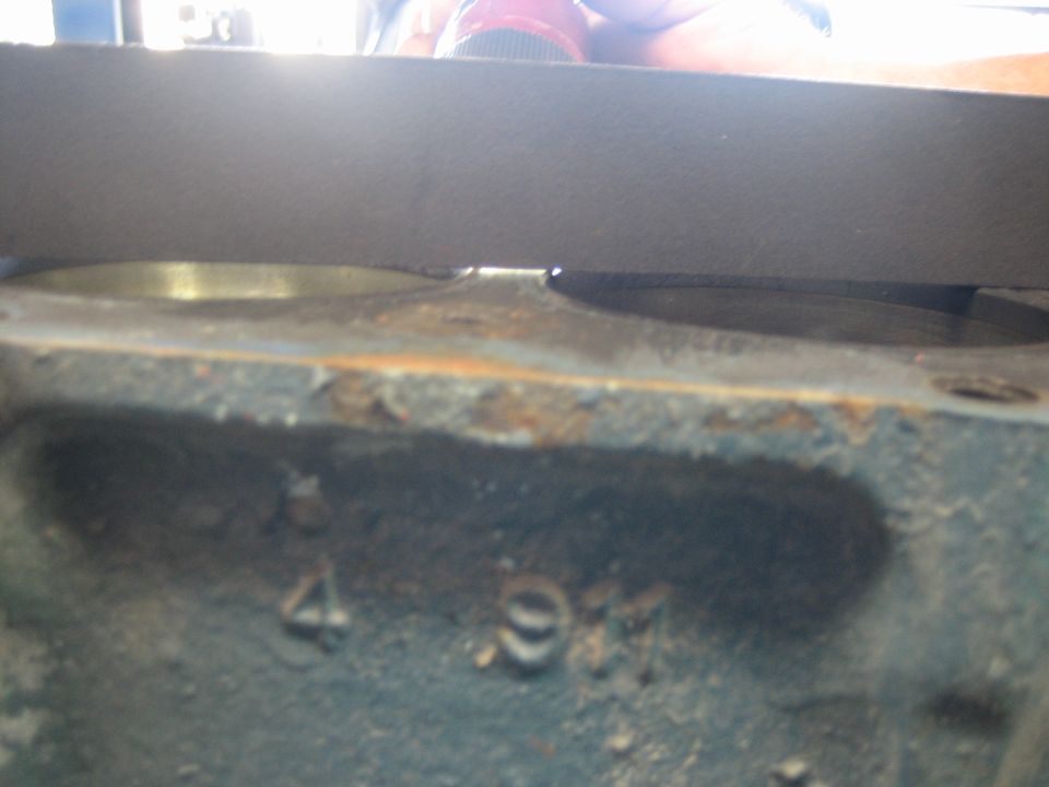 Engine block side with worn cast numbers near deck and straightedge on top