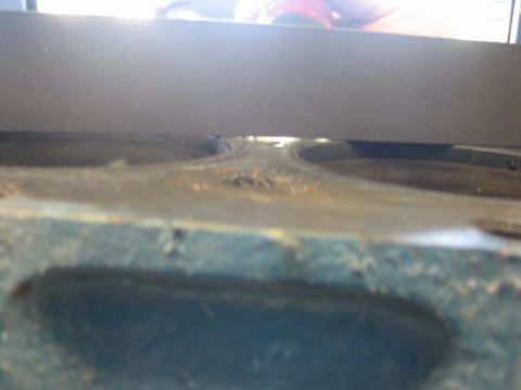 1998 Ford Crown Victoria - dark straightedge laid across an engine block deck to check the surface for warpage, with bores visible beneath.