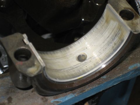 1998 Ford Crown Victoria - Close-up of a new main bearing half-shell with an oil feed hole installed in an engine block main cap.
