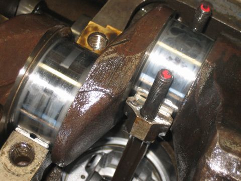 1998 Ford Crown Victoria - Polished crankshaft journals with main bearing caps and red-tipped stretch bolts during an engine bottom-end assembly.