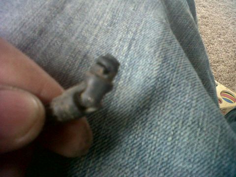2011 Ford 427 - A close-up view of a small, gray mechanical component being held by a person's fingers.