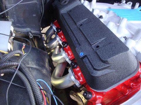 1989 Ford Bronco - Engine components, including a black valve cover and silver exhaust headers, are visible in this close-up shot.