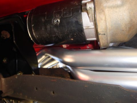 1989 Ford Bronco - Close-up view of a starter motor and exhaust pipes, part of a vehicle's engine bay.