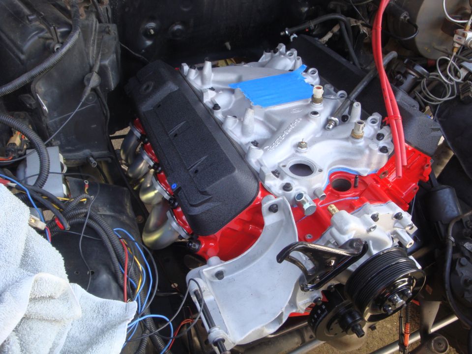 V8 engine with red block, silver intake manifold, and black valve covers, installed in engine bay