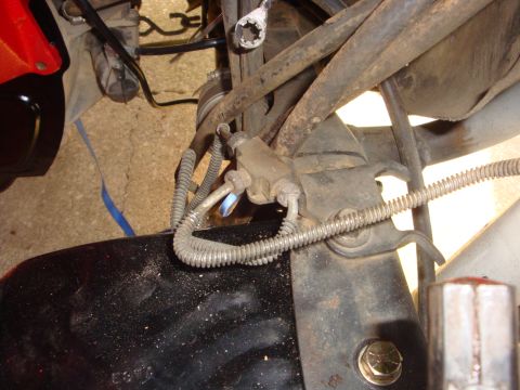 1989 Ford Bronco - Close-up view of vehicle undercarriage components, including brake lines and suspension parts.