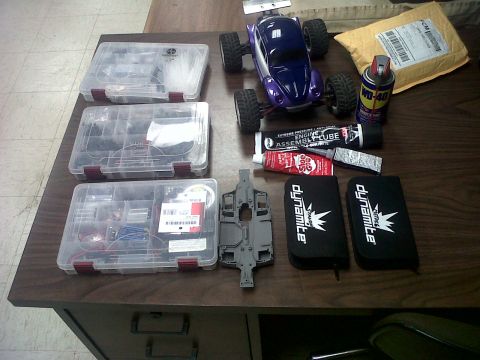 2011 Ford 427 - A purple radio-controlled car is laid out with various parts, tools, and storage cases on a wooden desk.