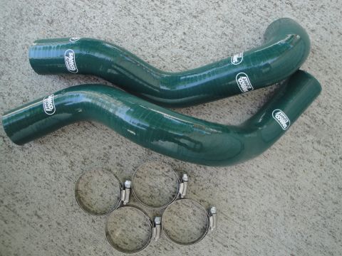 1995 Ford Taurus - Two green Samco Sport silicone hoses and four hose clamps are displayed on a concrete surface.