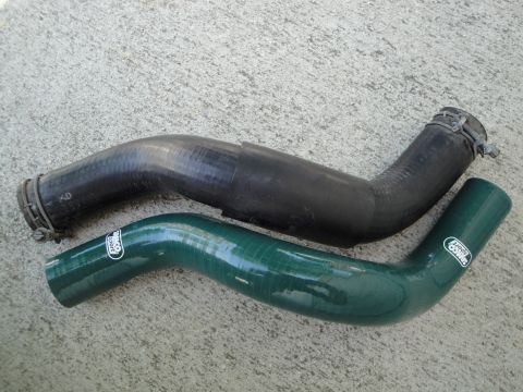 1995 Ford Taurus - A green silicone radiator hose with a 'Samco Sport' logo is shown next to a black rubber radiator hose on a concrete surface.