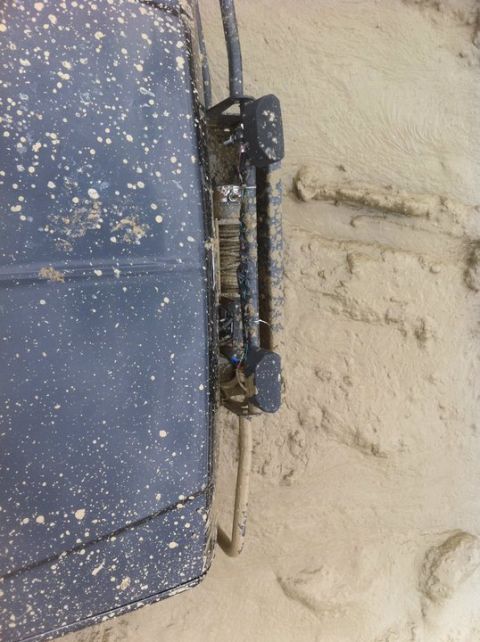 1990 Ford Bronco - Close-up of a mud-covered vehicle door edge with exposed wiring and a bracket.