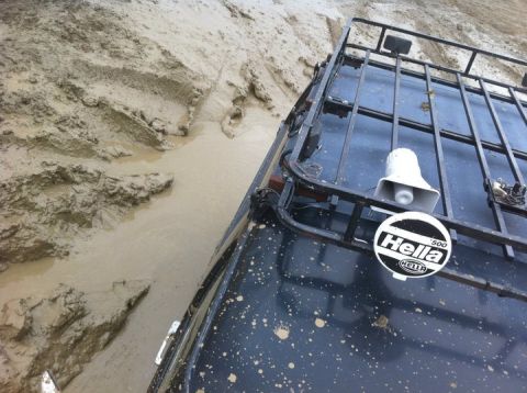1990 Ford Bronco - This vehicle is navigating a challenging muddy terrain, with its roof rack and Hella branding visible.
