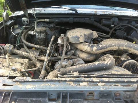 1990 Ford Bronco - The engine bay of a vehicle is heavily covered in mud, obscuring many details.