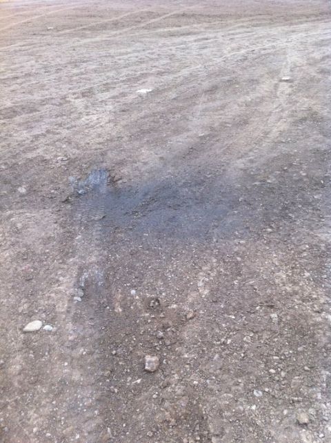 1990 Ford Bronco - Oil stain on dirt ground with visible tire tracks.