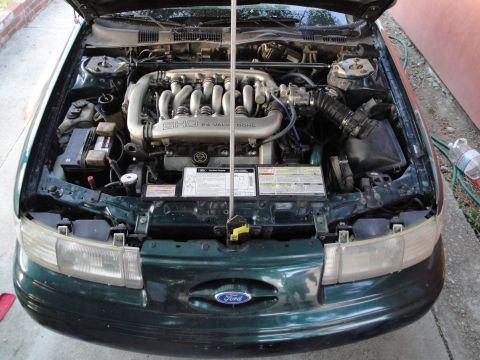 1995 Ford Taurus - The engine bay of a green 1995 Ford Taurus, showing the SHO 3.0L V6 engine.