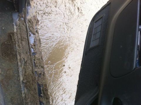 1990 Ford Bronco - The interior of a vehicle is heavily covered in mud, suggesting off-road use.