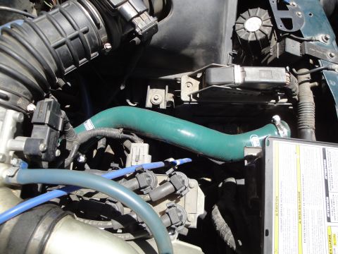 1995 Ford Taurus - Close-up view of an engine bay, highlighting a green silicone hose and a warning label with text.