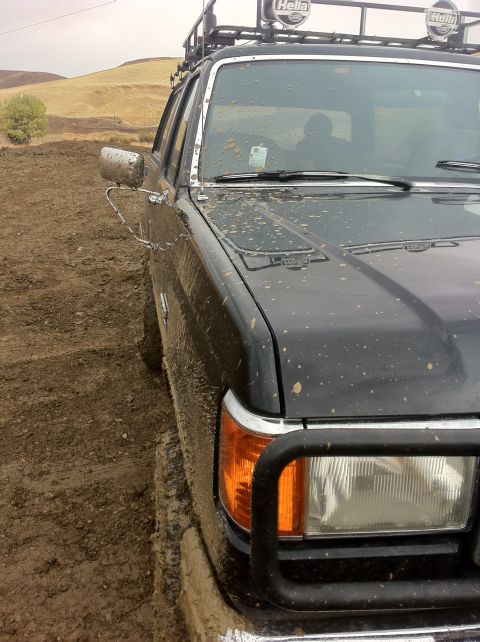 1990 Ford Bronco - Muddy 1990 Ford Bronco with roof rack and Hella lights, stuck in a dirt track.