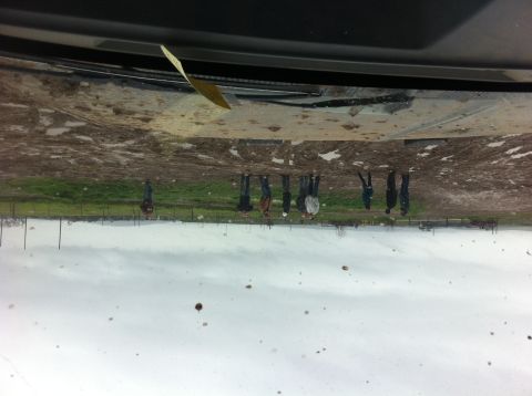 1990 Ford Bronco - A muddy windshield reflects a group of people standing in a field, with a Supermotors.net logo visible at the bottom right.