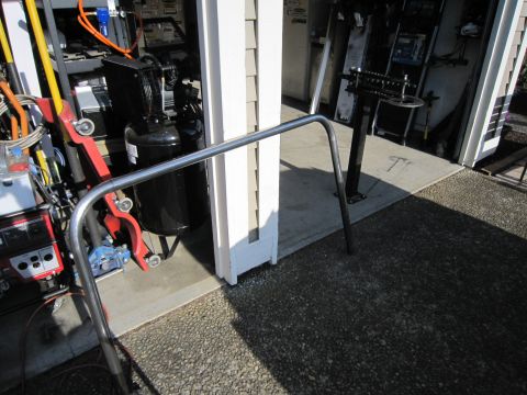 2008 Jeep Wrangler - A metal tube guard is positioned in front of a garage entrance, with various tools and an air compressor visible inside.