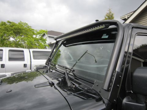2008 Jeep Wrangler - Close-up of a Jeep Wrangler's windshield frame, an aftermarket LED lightbar mounted above.