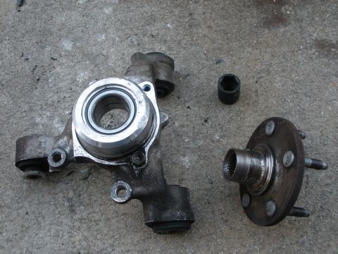 1995 Ford Thunderbird - Disassembled wheel bearing and hub assembly with a socket on a concrete surface.