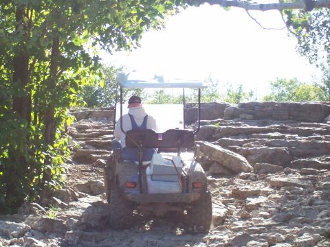 1978 Ford F-150 - A golf cart navigates a challenging rocky terrain on a sunny day.