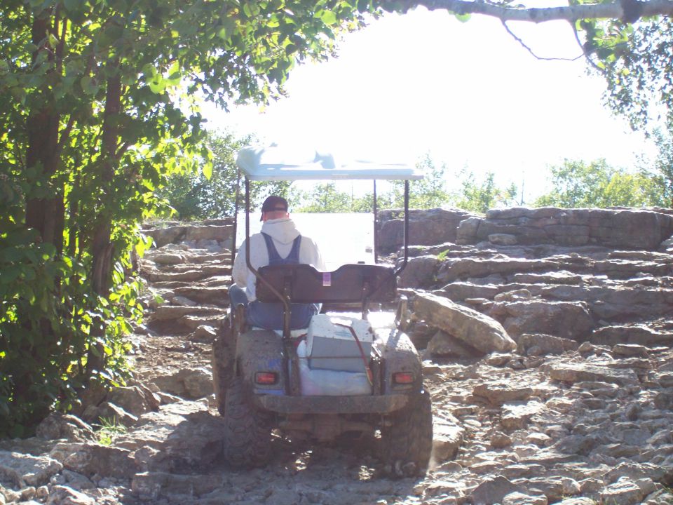 Golf cart with a person driving on a rocky trail