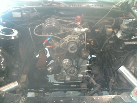 1987 Mazda RX-7 - Engine bay view showing the engine, alternator, and various hoses and wiring.