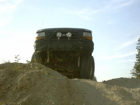 1995 Ford Bronco - This 1995 Ford Bronco is shown from the front, ascending a dirt mound under a clear sky.