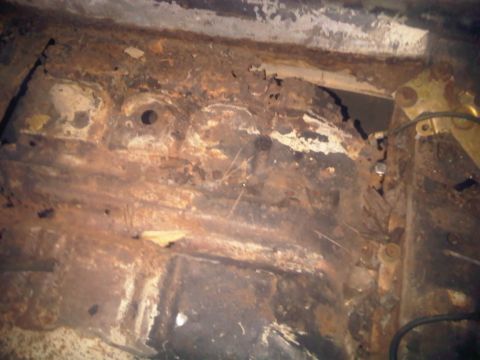 1973 Ford Ranchero - The undercarriage of a vehicle shows significant rust and deterioration, obscuring any specific details.