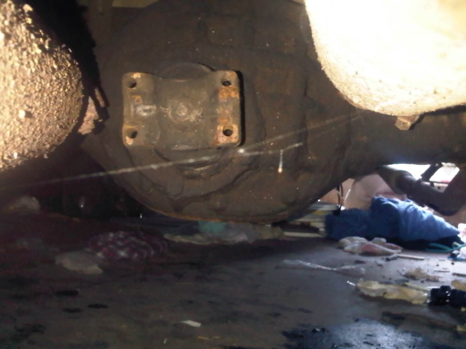 Close-up of a vehicle's rear differential and suspension components, with debris on the ground below