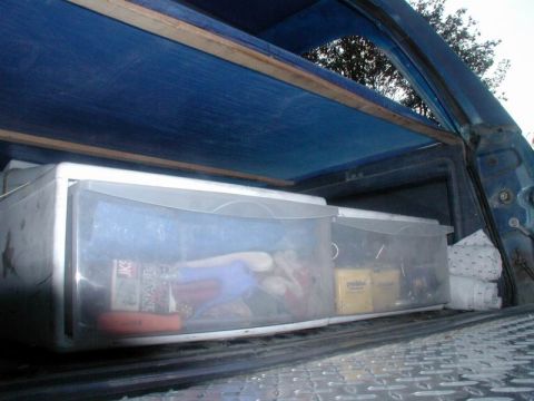 1985 Ford Bronco - Storage bins containing various items are visible in the cargo area of a vehicle.