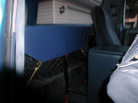 1985 Ford Bronco - The cargo area of a 1985 Ford Bronco, showing the spare tire covered by a blue tarp.