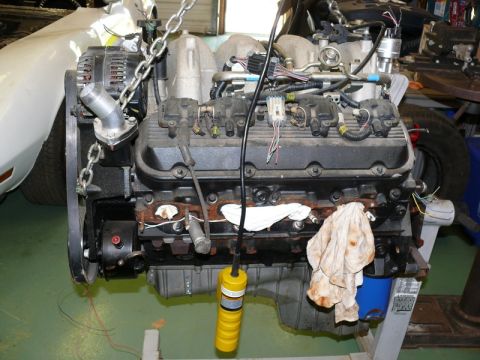1976 Chevrolet Corvette - Engine assembly suspended by chains, showing various components and wiring harnesses.