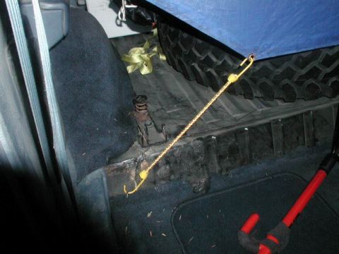 1985 Ford Bronco - Spare tire and jack secured in the cargo area of a 1985 Ford Bronco.
