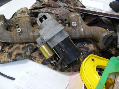 1976 Chevrolet Corvette - A starter motor and exhaust manifold are shown on a camouflage fabric background.