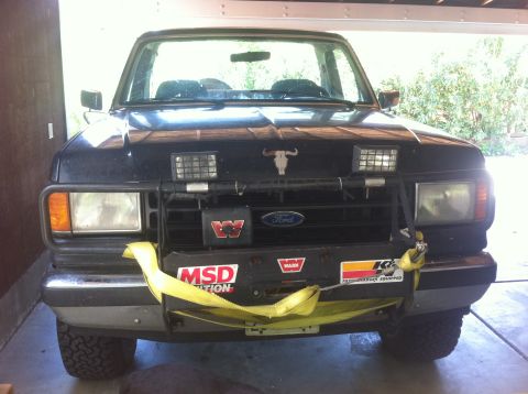 1990 Ford Bronco - Front view of a black Ford Bronco with a winch and auxiliary lights mounted on the grille guard.