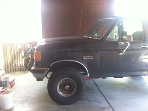 1990 Ford Bronco - This Ford Bronco is parked indoors, showing its side profile and front fender detail.