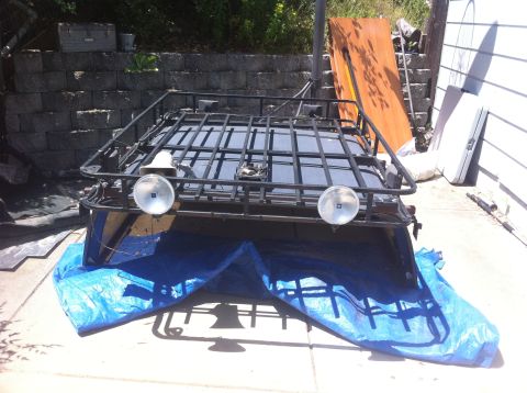 1990 Ford Bronco - A roof rack with two round auxiliary lights is shown, partially covered by a blue tarp.