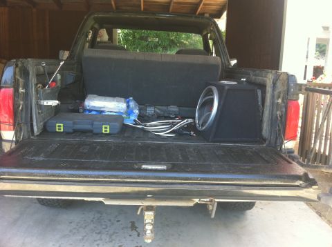 1990 Ford Bronco - The rear of a 1990 Ford Bronco is shown with the tailgate down, revealing a subwoofer and various tools inside.