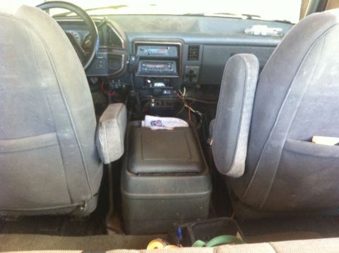 1990 Ford Bronco - The interior of a truck shows the dashboard, center console, and front seats, with visible wiring.