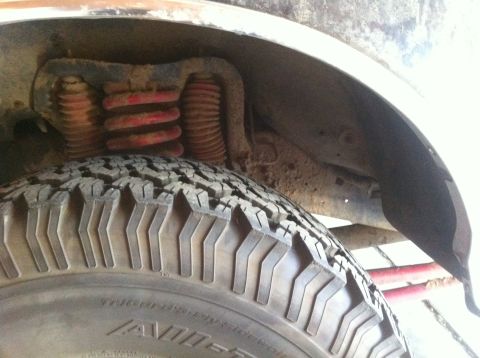 1990 Ford Bronco - Close-up view of suspension components and tire in a vehicle's wheel well.
