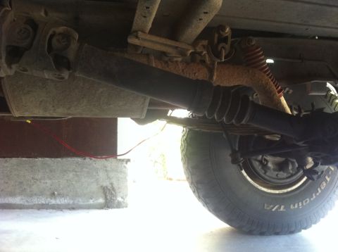 1990 Ford Bronco - A close-up view of the undercarriage reveals the rear axle, driveshaft, and tire of a vehicle.
