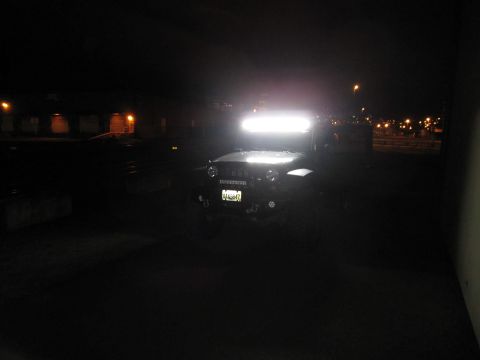 2008 Jeep Wrangler - Night shot of a dark Jeep Wrangler with its windshield-mounted LED light bar blazing white above the hood, illuminating an otherwise pitch-…