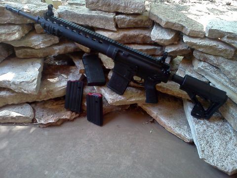 1996 Ford Bronco - An assault rifle with three magazines is displayed against a backdrop of large stones.