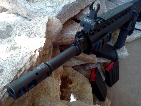 1996 Ford Bronco - This image shows an assault rifle with its barrel and magazines visible, set against a backdrop of rocks.