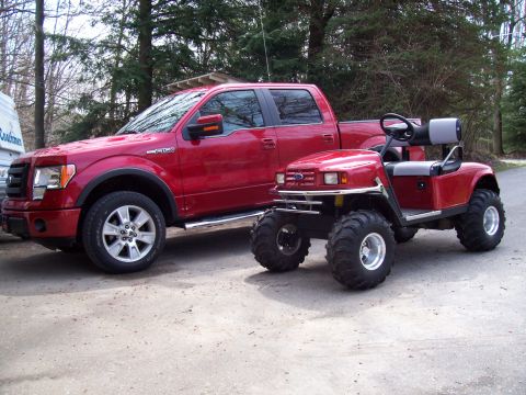 1978 Ford F-150 - A red Ford F-150 pickup truck is parked beside a modified red golf cart with large off-road tires.