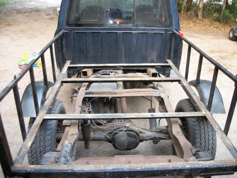 1994 Ford Explorer - The rear chassis and bed frame of a dark blue truck are visible, showing exposed mechanical components.
